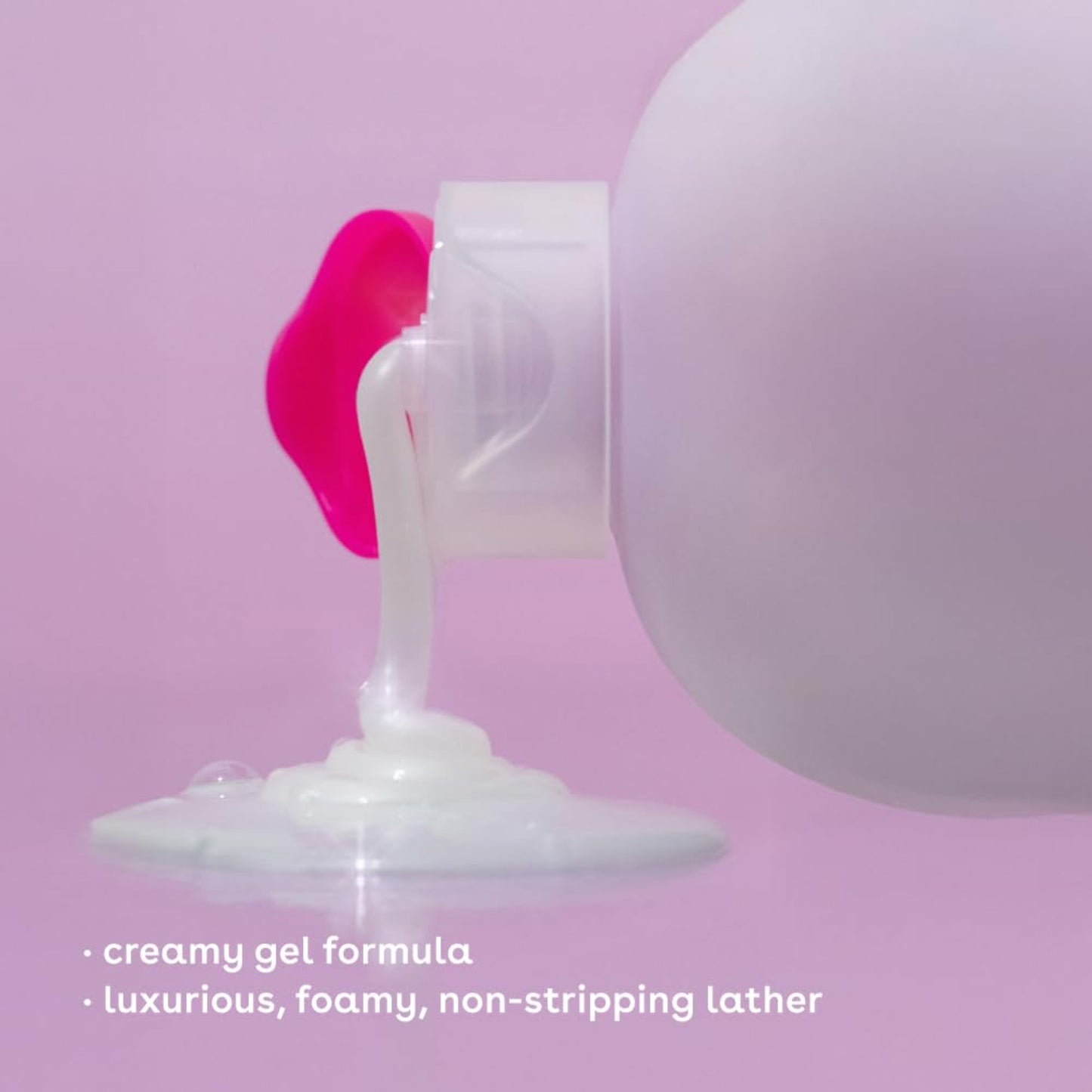 White bottle with pink cap dispensing creamy gel onto a white surface against a pink background