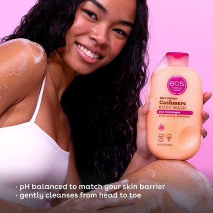 Woman with soap suds on her body holding an eos body wash bottle against a pink background