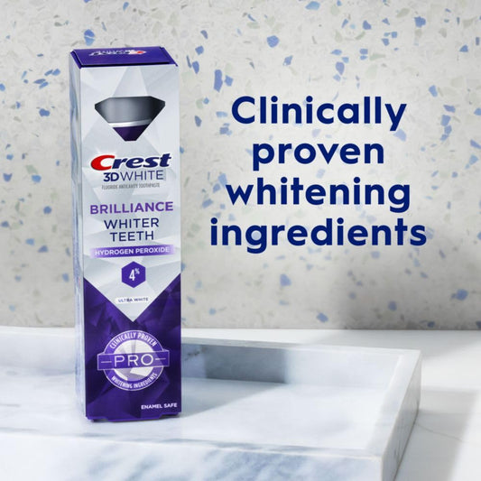 Crest 3D White toothpaste box with text about whitening ingredients on a bathroom counter.