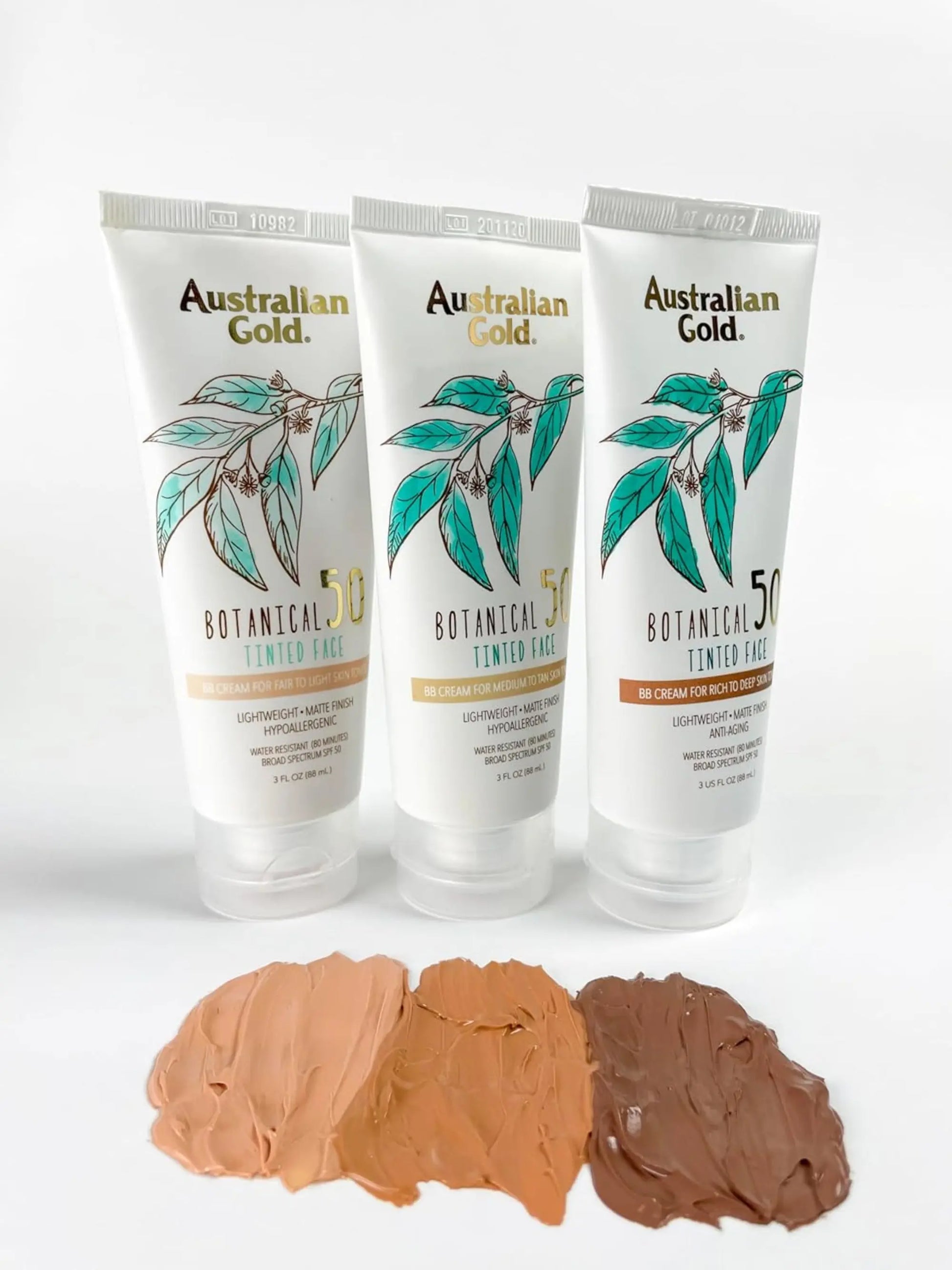Three tubes of Australian Gold Botanical Tinted Tan with color swatches on a white background