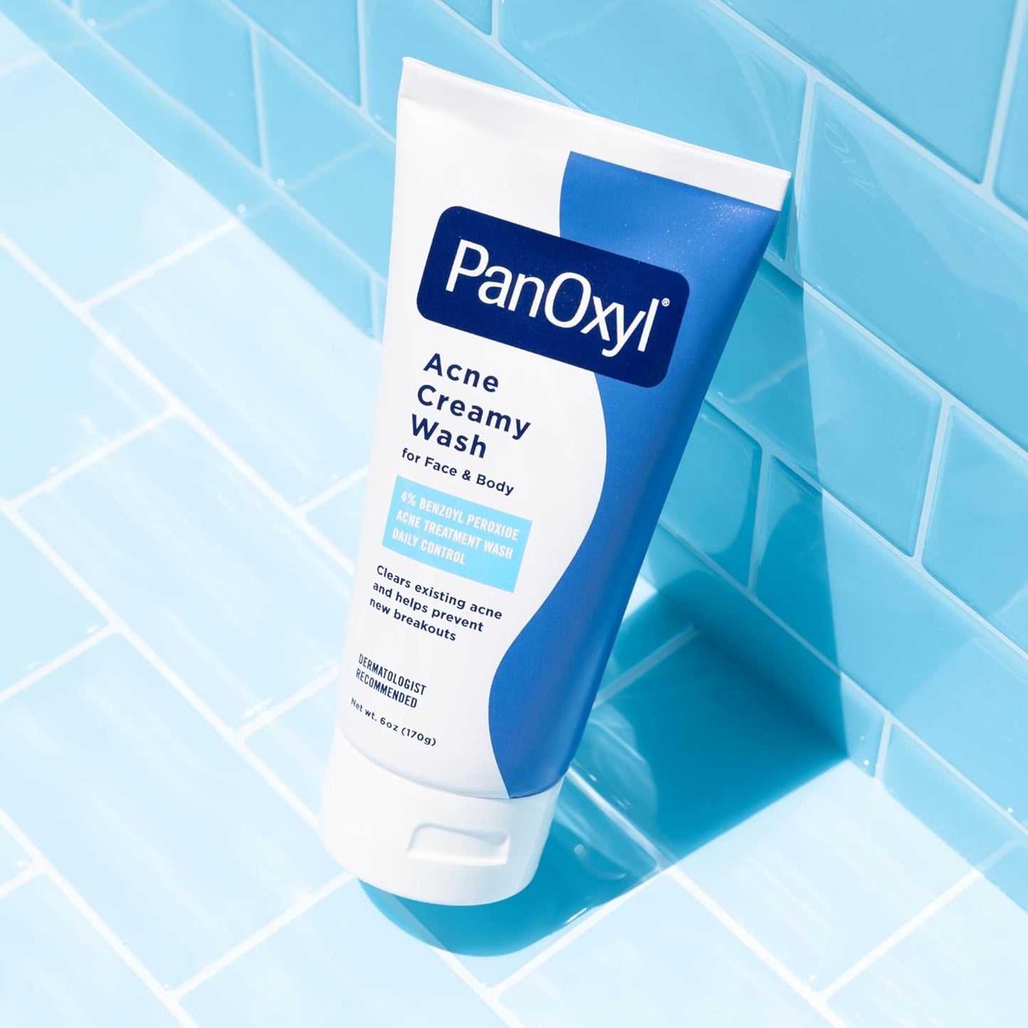 PanOxyl Acne Creamy Wash tube on a blue tiled bathroom floor