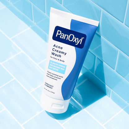 PanOxyl Acne Creamy Wash tube on a blue tiled bathroom floor