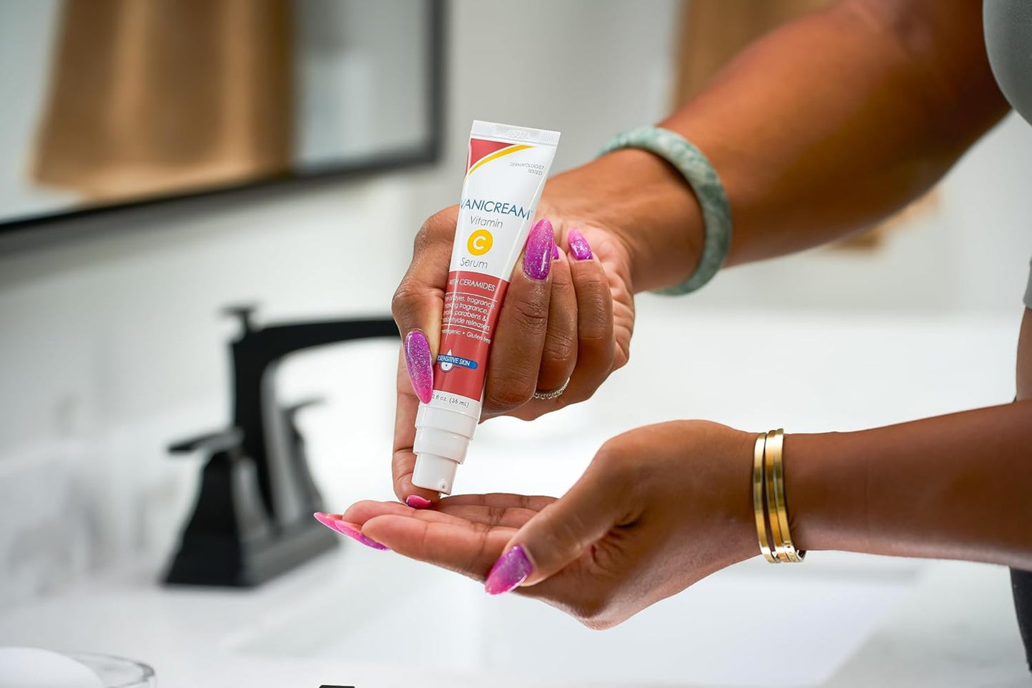 Person applying a tube of Vaseline hand cream to their hand in a bathroom setting.