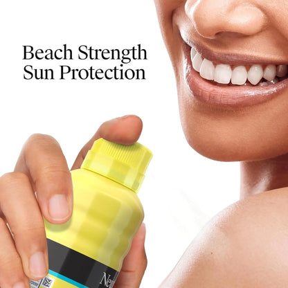 Person holding a yellow sunscreen bottle with 'Beach Strength Sun Protection' text.