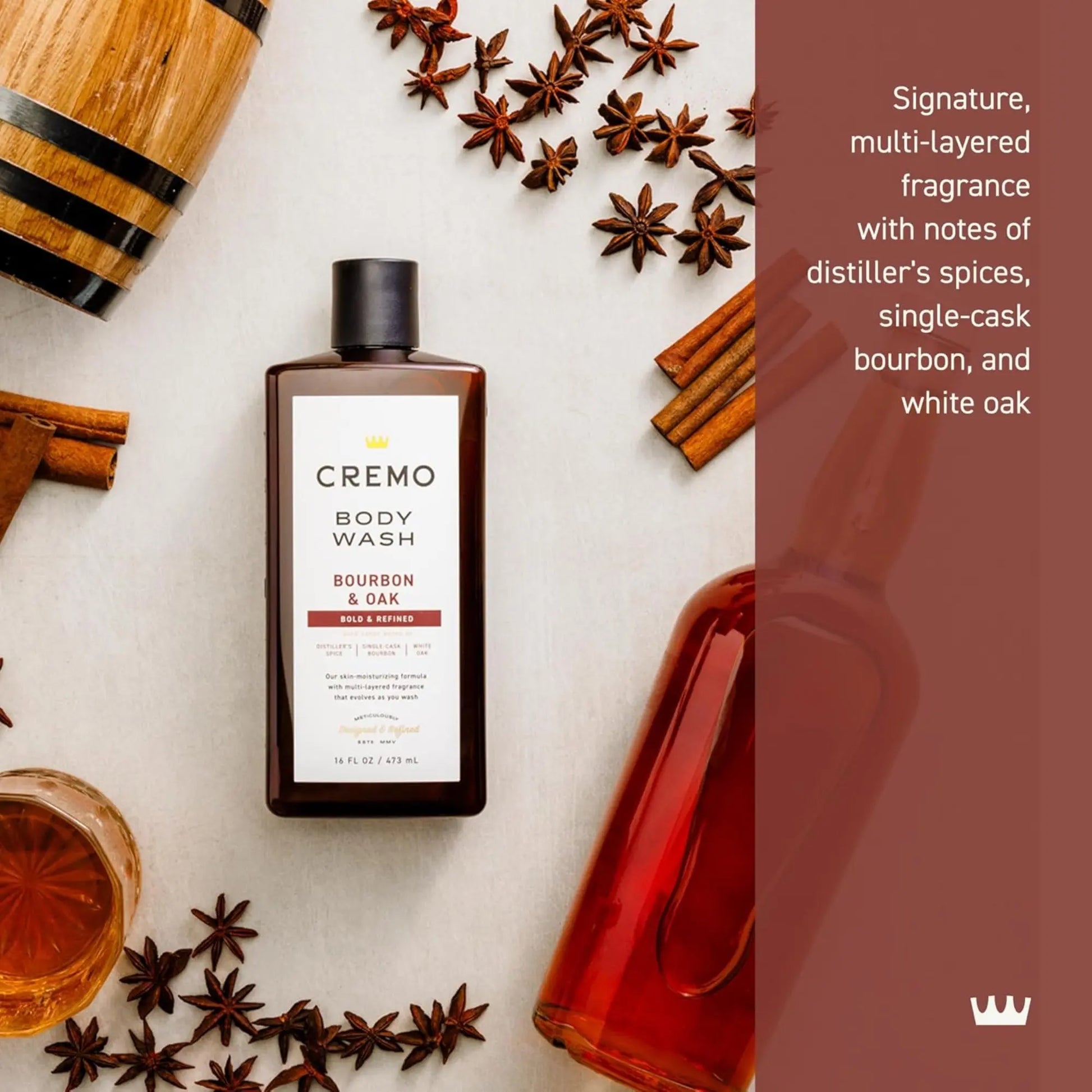 Cremo Body Wash bottle with bourbon and oak theme on a white surface with spices and barrel.