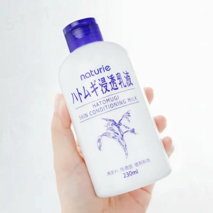 Naturie body wash bottle held in a hand with a white background