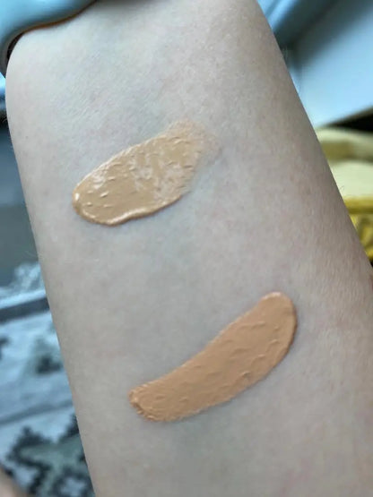 Two swatches of beige makeup on a person's arm