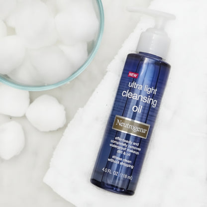 Neutrogena ultra light cleansing oil bottle with cotton balls on a white background
